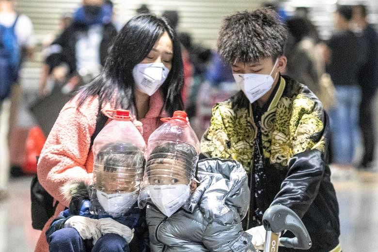 Children wearing improvised face protectors made from water bottles at Guangzhou international airport in China on Saturday. The usually busy airport appeared deserted following the suspension of many flights.