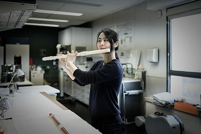 Musician Mina Jang plays the 3D-printed replica of a wooden transverse flute at the music lab of the Museum of Music in Paris.