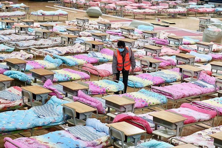A worker setting up beds yesterday at the Hongshan Stadium to help convert the sports facility into a makeshift hospital following the coronavirus outbreak in Wuhan, Hubei province.
