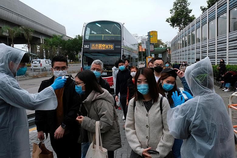 Volunteers checking people's temperatures at a bus stop in Tin Shui Wai, a border town in Hong Kong, yesterday. The city now has 17 confirmed infections, with four suspected to be local transmissions.