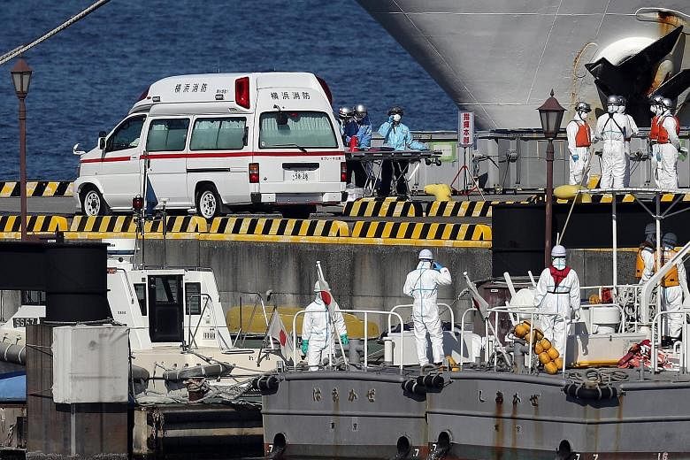 Above: Passengers were barred from leaving the World Dream, which is docked in Hong Kong, after three people who were on the ship tested positive for the coronavirus. Left: An ambulance and Japan Coast Guard members at Yokohama port awaiting the arri