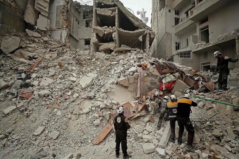 Rescue workers searching for victims amid the rubble of a building that was hit during an air strike by Syrian forces on the rebel-held town of Ariha in the northern countryside of Syria's Idlib province yesterday. Syria has pressed on with its offen