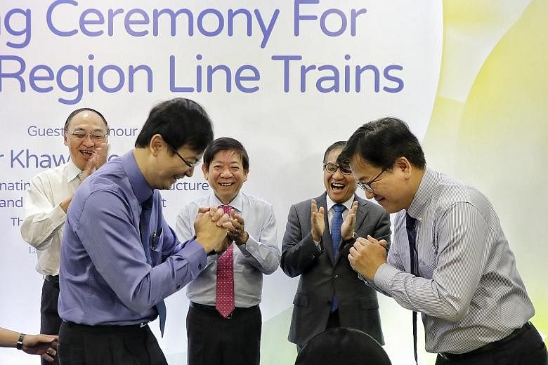Mr Ngien Hoon Ping (in blue), LTA chief executive, and Mr Choi Dong-hyun, vice-president and chief operating officer of railway business division at Hyundai Rotem, congratulating each other after the signing ceremony. Looking on are (from left) LTA c
