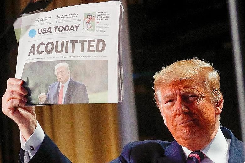 US President Donald Trump holding up a copy of USA Today's front page showing news of his acquittal in his Senate impeachment trial, as he arrived to address the National Prayer Breakfast in Washington yesterday. SEE WORLD A13