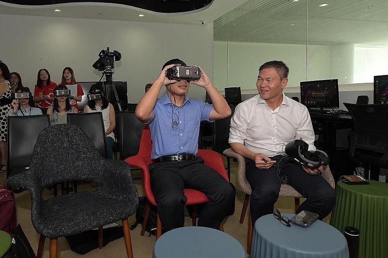 Minister for Social and Family Development Desmond Lee (centre) and Touch Community Services chief executive James Tan trying on virtual reality headsets at Touch Community Services at Leisure Park Kallang yesterday. Mr Lee tried out the Virtual Real