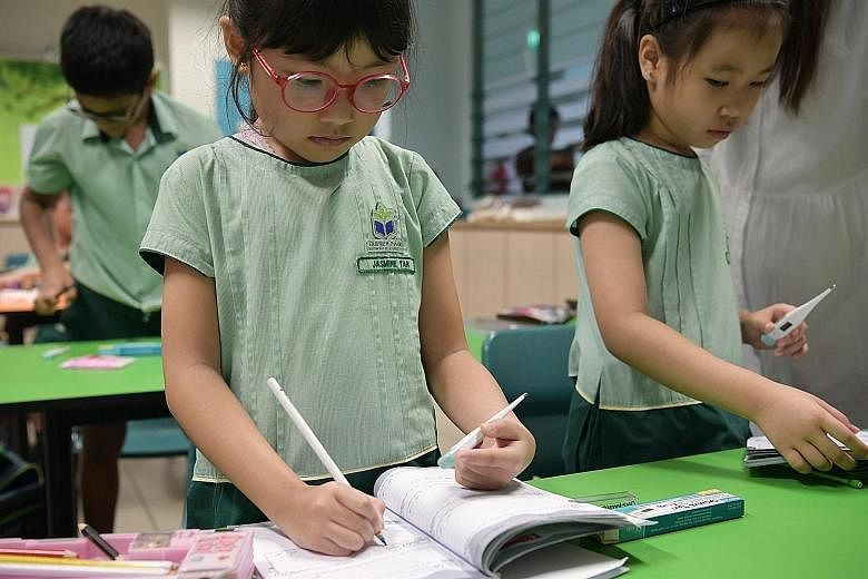 Above: Farrer Park Primary School pupils taking turns to wash their hands before going for recess yesterday morning. Left: Primary 2 pupils at Farrer Park Primary School recording their temperatures in their books after a temperature-taking exercise 