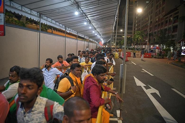 Food handlers at the Loyang Tua Pek Kong Temple wore masks as a safety precaution. The celebrations this year saw a smaller than usual turnout, with just 3,000 attending, compared to 5,000. Left: Staff from the Hindu Endowments Board monitoring therm