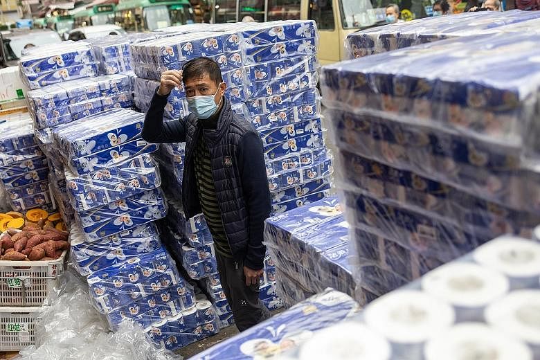A man standing amid stacks of toilet paper outside a pharmacy in Hong Kong yesterday. Residents have been stockpiling essentials and toilet paper for fear of supply shortage.