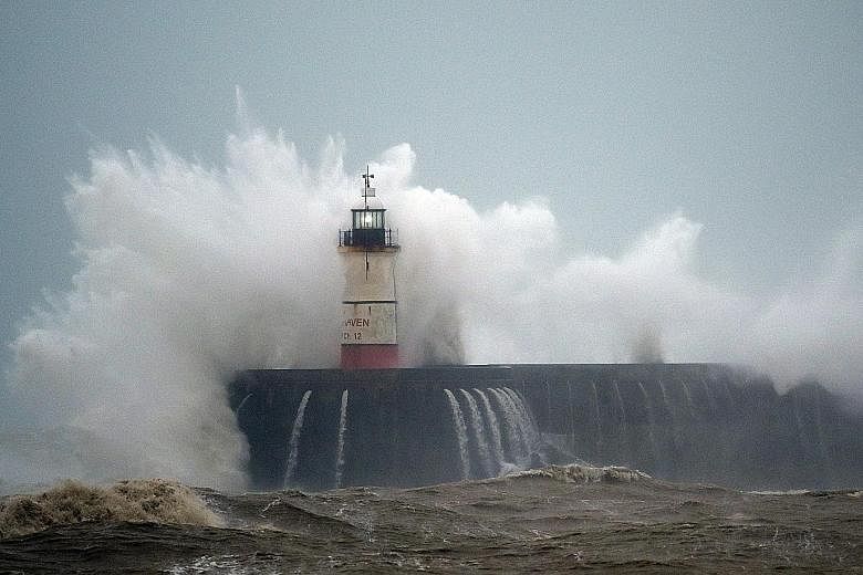 Waves crashing over the Newhaven Lighthouse on the south coast of Britain yesterday.