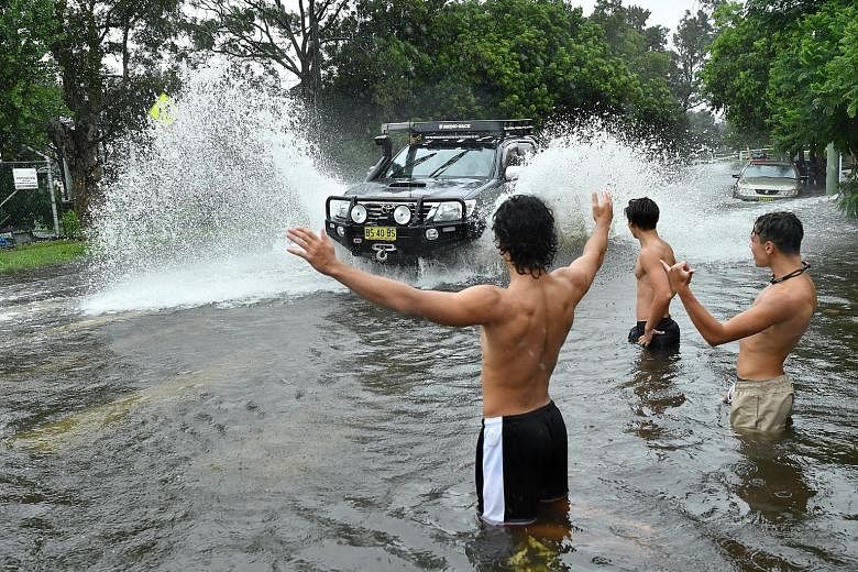Trees swaying in Dampier, Western Australia, as Tropical Cyclone Damien made landfall in the state on Saturday, bringing winds of up to 200kmh. PHOTO: REUTERS A group of young men directing traffic through flood waters in Sydney, Australia, yesterday