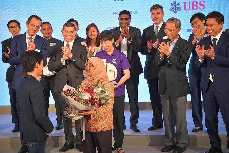 President Halimah Yacob receiving a bouquet from two young finalists of the award - siblings and students Seng Ian Hao and Seng Ing Le - during yesterday's ceremony.