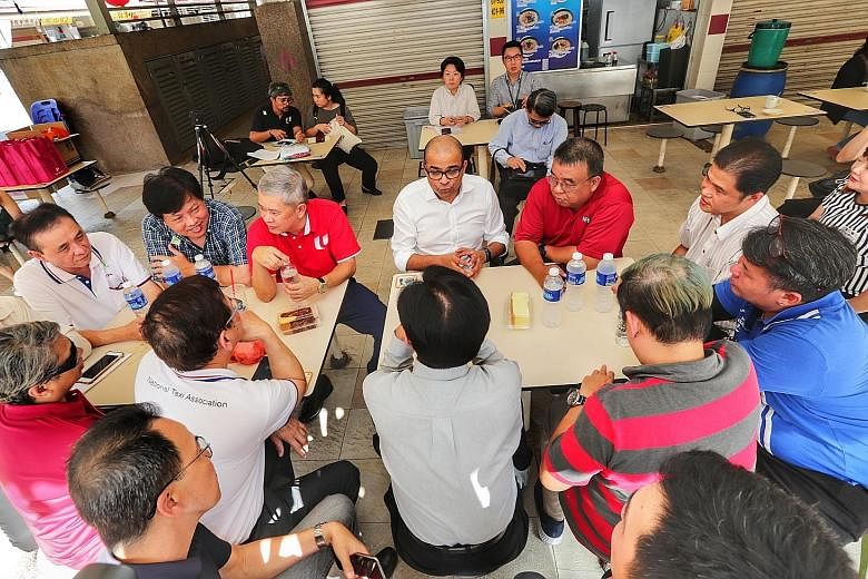 Senior Minister of State for Transport Janil Puthucheary (centre), with Mr Ang Hin Kee (third from left), adviser to the National Taxi Association and National Private Hire Vehicles Association, speaking to drivers yesterday about the relief package,