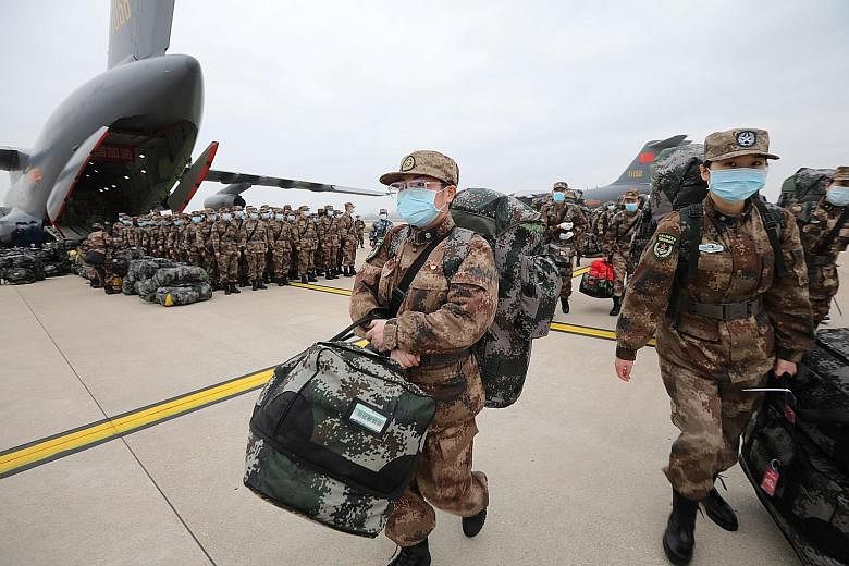 Personnel with medical supplies disembarking from Chinese People's Liberation Army Air Force planes at the Wuhan Tianhe International Airport in Hubei province yesterday.