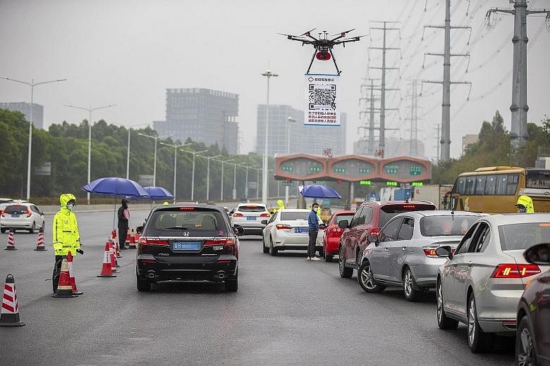 A drone with a QR code poster broadcasting audio messages asking motorists to scan the code and register their details online, to minimise contact with personnel and speed up inspection, in Shenzhen, in southern Guangdong province, on Tuesday.