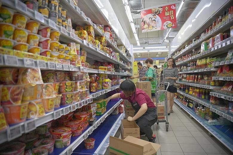 Shelves of daily essentials as well as instant noodles being refilled at a FairPrice outlet at Block 212 Bedok North Street 1.Price Finest outlet in Paya Lebar (above) walking past empty shelves last Saturday.