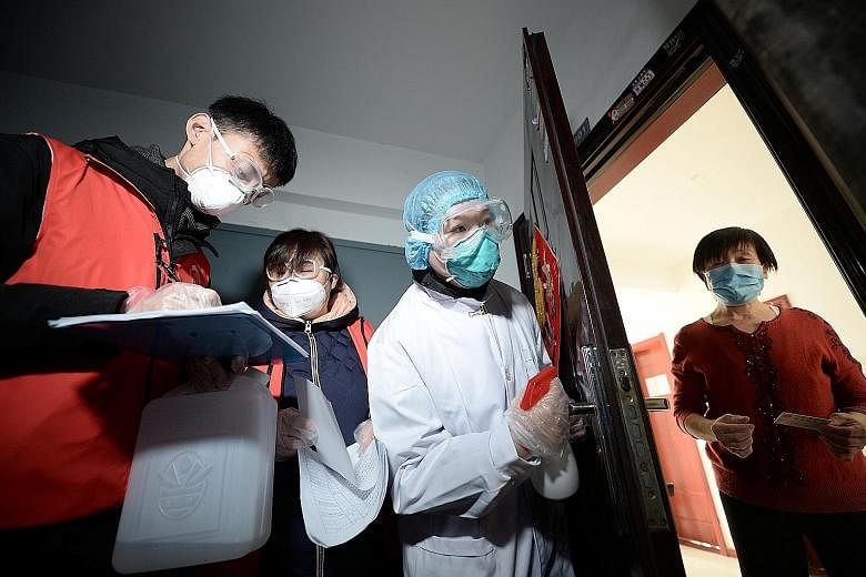 Community workers and medical staff visiting a woman at her home in Tianjin on Wednesday as they conducted door-to-door searches to inspect residents during the current coronavirus outbreak.