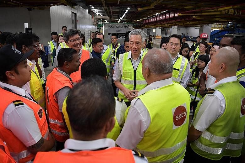 Prime Minister Lee Hsien Loong and Senior Minister of State for Transport and Health Lam Pin Min visiting baggage handling workers at Changi Airport Terminal 3 yesterday. PM Lee said the economic impact of the virus outbreak, particularly in the next