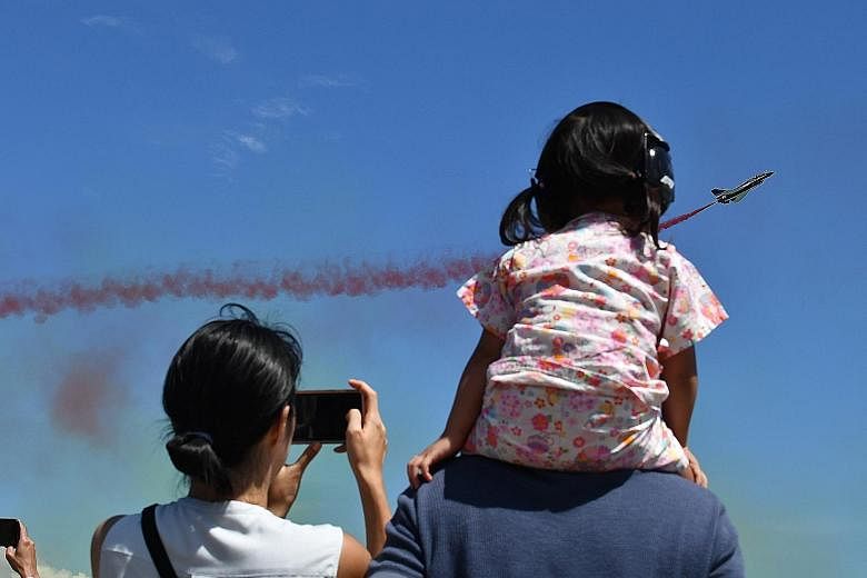 Above: A visitor taking photographs of an F-15SG aircraft. Left: A person dressed as superhero Deadpool posing in front of the Royal Malaysian Air Force's SU-30MKM. Justice League and Marvel characters were among the highlights at the airshow yesterd
