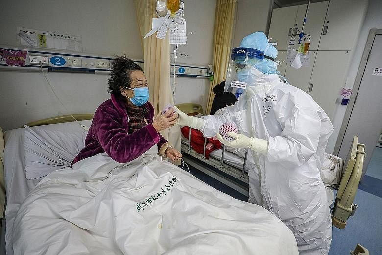 Medical workers treating a coronavirus patient at the Wuhan Red Cross Hospital on Sunday. The death toll now stands at 1,770 in China.