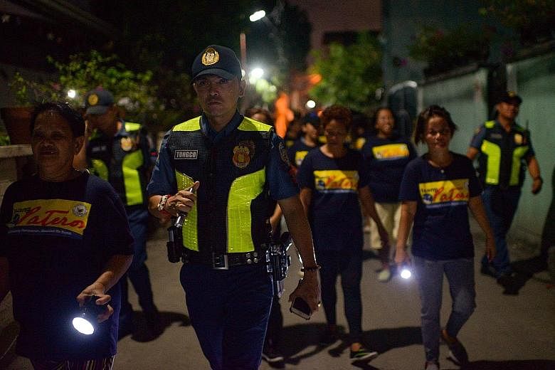 The "women's patrol", a group of Philippine mothers and grandmothers, patrolling the streets of Pateros, Manila, with police officers in December last year. They believe their nightly walks have been helping to deter shadowy gunmen behind the murders