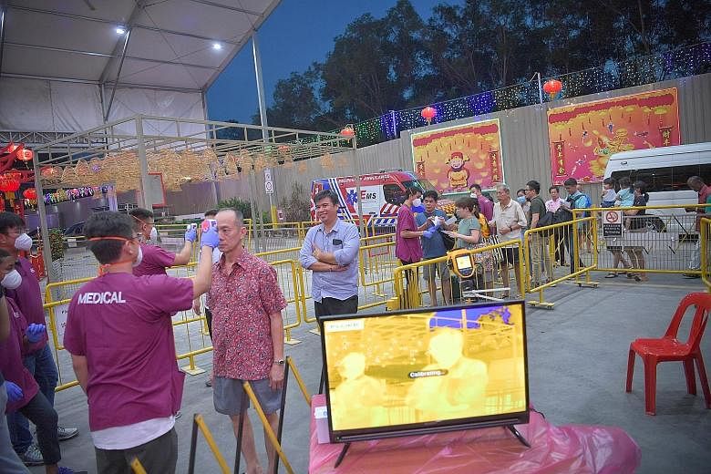 Medical staff from the Singapore Ambulance Association taking the body temperature of visitors before they entered the Loyang Tua Pek Kong Temple on Feb 7. ST PHOTO: ARIFFIN JAMAR