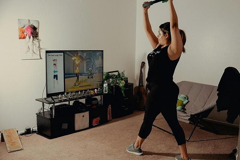 Student Tiffany Ruiz (right) works out with Nintendo's Ring Fit Adventure game (left) at her home in Bakersfield, California.