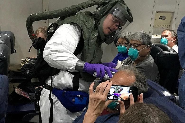 A worker in a protective suit checking the temperatures of passengers who were on board the Diamond Princess cruise ship, on a chartered evacuation aircraft from Tokyo's Haneda Airport, en route to Lackland Air Force Base in the US on Monday.