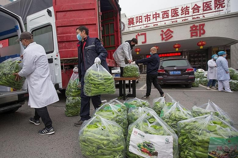 Medical workers receiving chillies donated from Shandong province at a hospital in the city of Xiangyang, in Hubei province, yesterday. Hubei has rolled out a slew of stricter measures this week, including lockdowns in communities and a ban on all mo