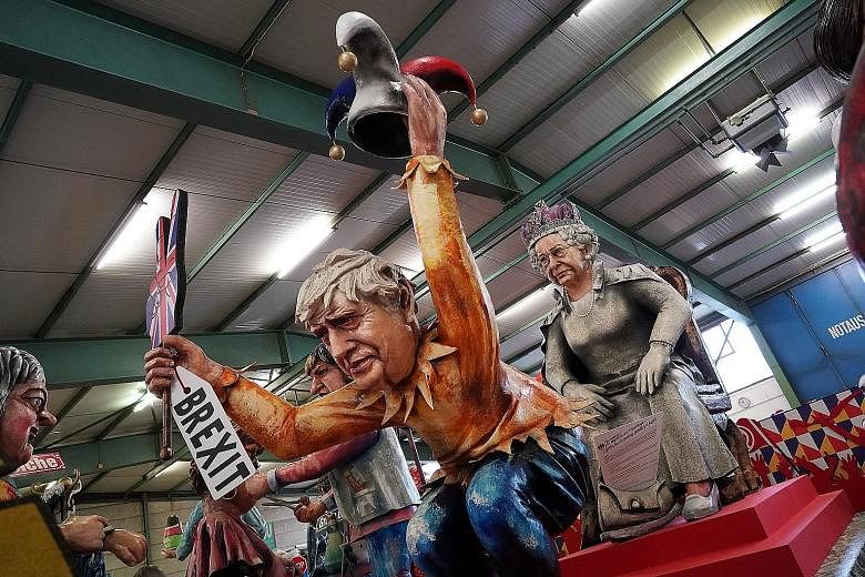 A float depicting British Prime Minister Boris Johnson holding a Brexit sign and a fool's hat and crouching in front of Queen Elizabeth, being presented to the media by the Mainz Carnival Association in Germany on Tuesday. The British have pledged to