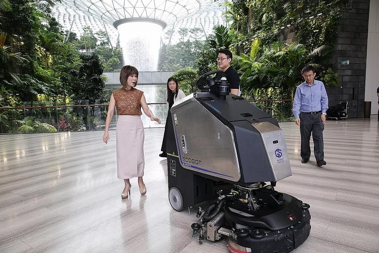 Senior Minister of State for the Environment and Water Resources Amy Khor (far left) being shown an Ecobot autonomous scrubber at work by Gaussian Robotics' head of business development Kevin Lee (in black) yesterday. With them were Jewel Changi Airp