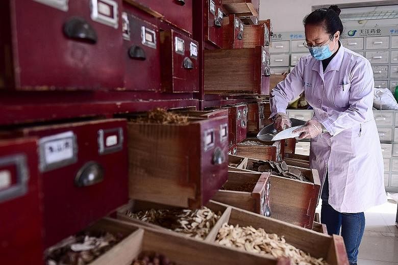 A staff member preparing traditional Chinese medicine at a Liaoning hospital on Thursday. China has turned to TCM along with Western treatment as part of clinical trials to overcome the coronavirus epidemic.