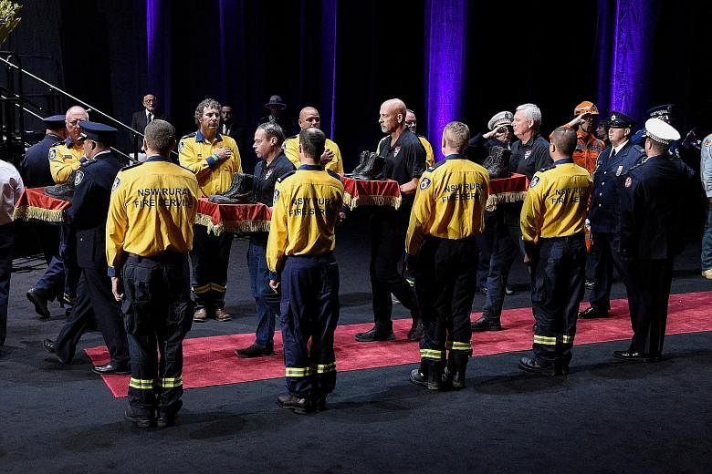A guard of honour carrying six pairs of boots, in tribute to three Australian volunteers and three US firefighters who died battling the blazes in New South Wales, during a public ceremony in Sydney yesterday. The bush fires, which lasted from Septem
