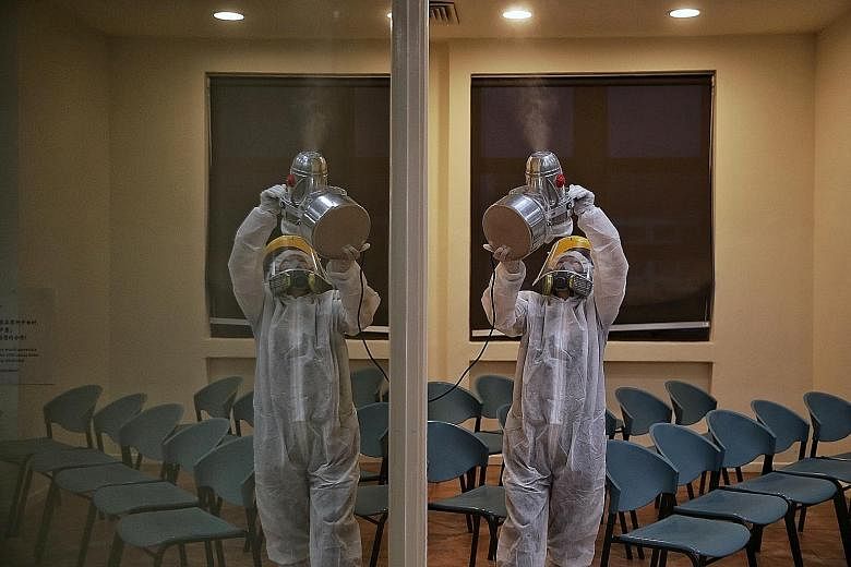 Senior operations manager Jun Tay of Conrad Maintenance Services disinfecting a place visited by a confirmed coronavirus patient. The protective gear she has to don is warm and uncomfortable to wear.