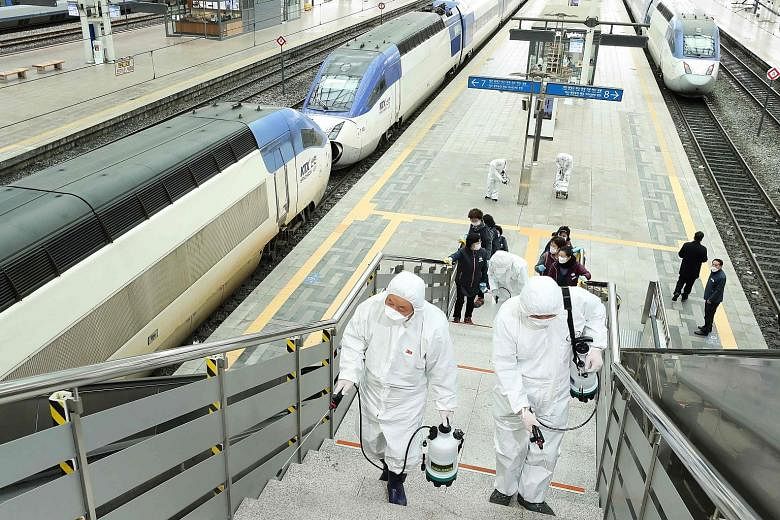 Railway workers in protective gear spraying disinfectant as part of preventive measures against the spread of the coronavirus, at a Seoul railway station yesterday. South Korea's hard-hit Kospi index rebounded 1.18 per cent yesterday.