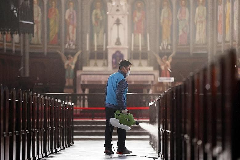 A worker disinfecting Myeongdong Catholic Cathedral in Seoul yesterday. The number of infections continued to surge in South Korea yesterday, with cases in Seoul and Busan coming mainly from small clusters at churches and hospitals.