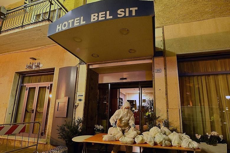 A civil protection and health worker in a protective suit and mask delivering the evening meal at the Hotel Bel Sit in Alassio, northern Italy, where 34 people are being quarantined.