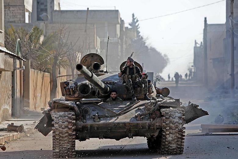 Turkey-backed Syrian fighters riding in a tank on Thursday in the town of Saraqib, in the eastern part of Syria's Idlib province.