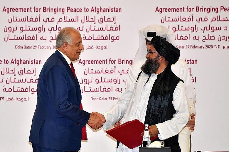 US special envoy Zalmay Khalilzad and Taleban political chief Mullah Abdul Ghani Baradar after signing the peace agreement in Doha, Qatar, yesterday. Afghans in Jalalabad city in eastern Afghanistan celebrating on Friday in anticipation of the US-Tal