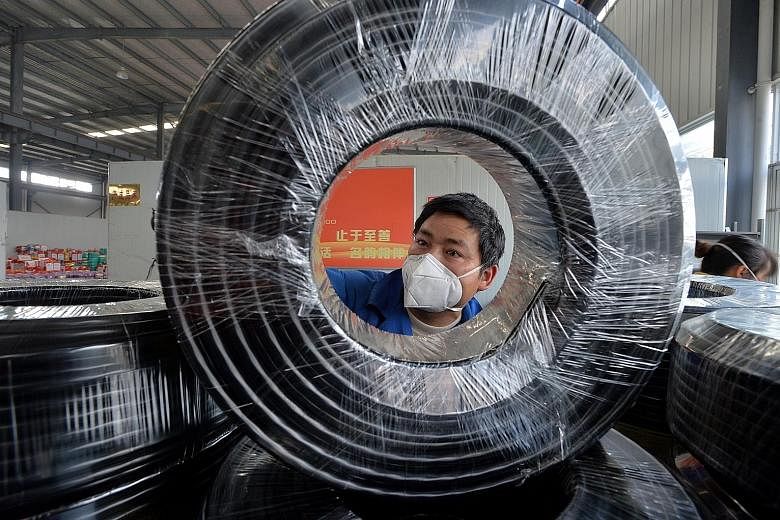 A masked worker working on a production line manufacturing cables at a factory in Guiyang, Guizhou province. The Chinese government has called on businesses to resume as soon as possible but many migrant workers have not returned to work because of t