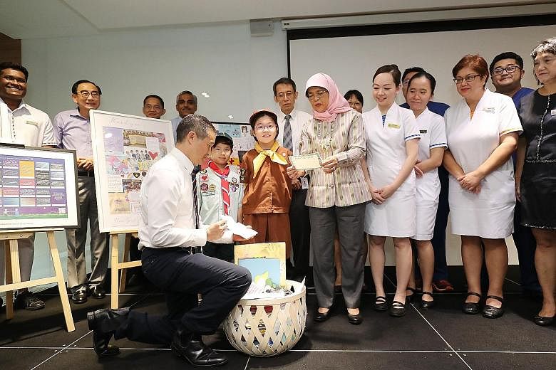 President Halimah Yacob and Professor Kenneth Kwek, SingHealth's deputy group chief executive, looking at some of the cards written by Scouts and Guides here. With them were Singapore General Hospital senior management and staff, who received the let