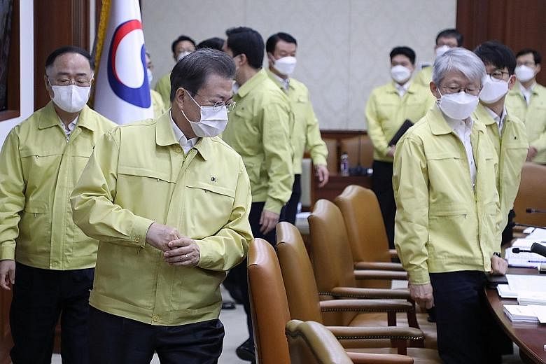 South Korean President Moon Jae-in (second from left) and his ministers at a Cabinet meeting in Seoul yesterday. He revealed plans to provide 30 trillion won (S$34.9 billion) in funding to fight the virus, and urged a "bold fiscal injection" to cushi