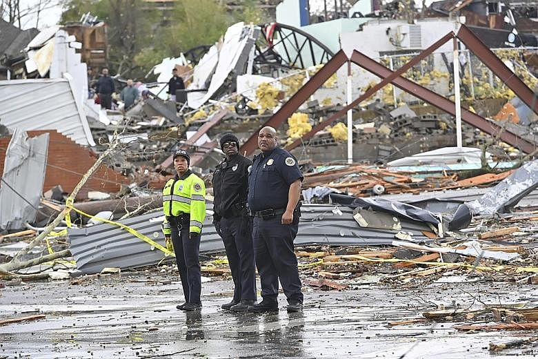 Police officers in a damaged part of tornado-hit Nashville, capital of Tennessee, yesterday. The twisters touched down shortly after midnight on Tuesday, destroying buildings and toppling power lines hours before the southern US state voted in the Su