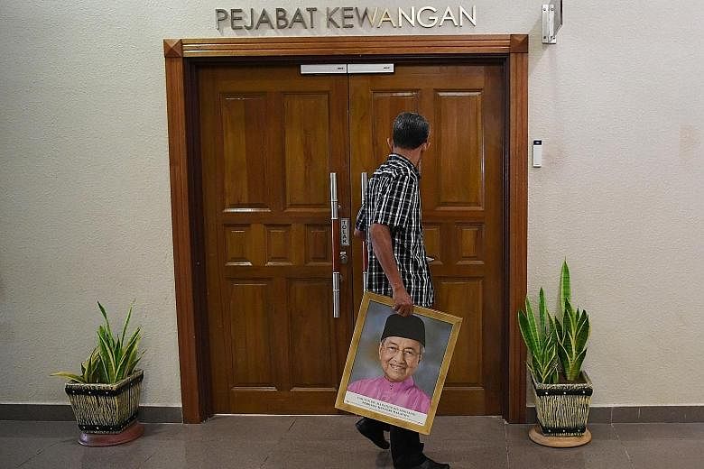 An official removing a picture of former premier Mahathir Mohamad at a court in Kuantan this week. New Premier Muhyiddin Yassin is facing pressure from both sides of the political divide, but he appears more focused on steadying the administration in