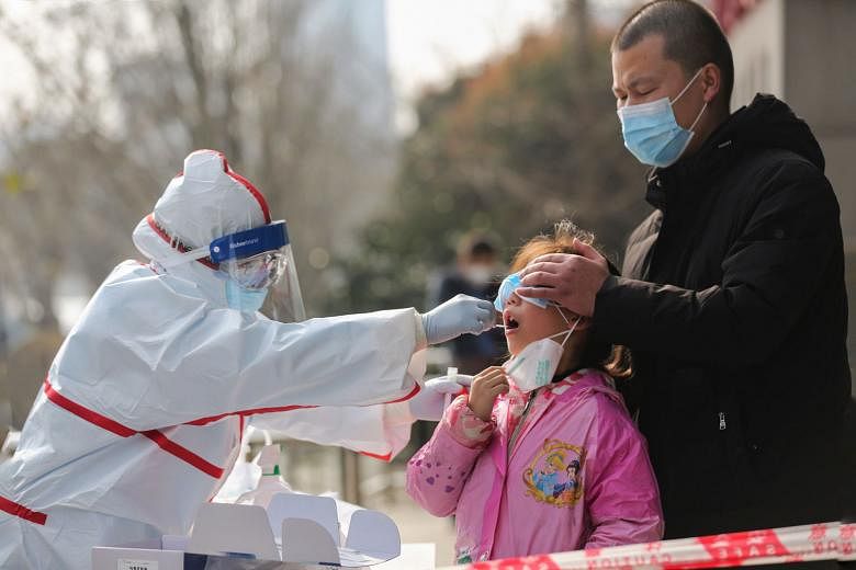 A medical worker collecting a sample from a girl to be tested for the coronavirus at a residential area in Wuhan, Hubei province yesterday. With a steady drop in new cases in recent weeks, China is now concerned about imported infections, with the vi