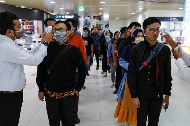 Medical officers checking passengers' temperature at a Mass Rapid Transit station in Indonesia, after the nation confirmed its first cases.