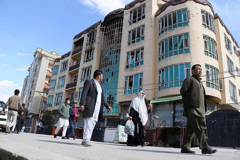 Residents in Kabul yesterday walking past a damaged building at the site of Friday's assault. Gunmen opened fire at a crowded political rally in the attack, which was the deadliest assault in Afghanistan since the US signed a withdrawal deal with the