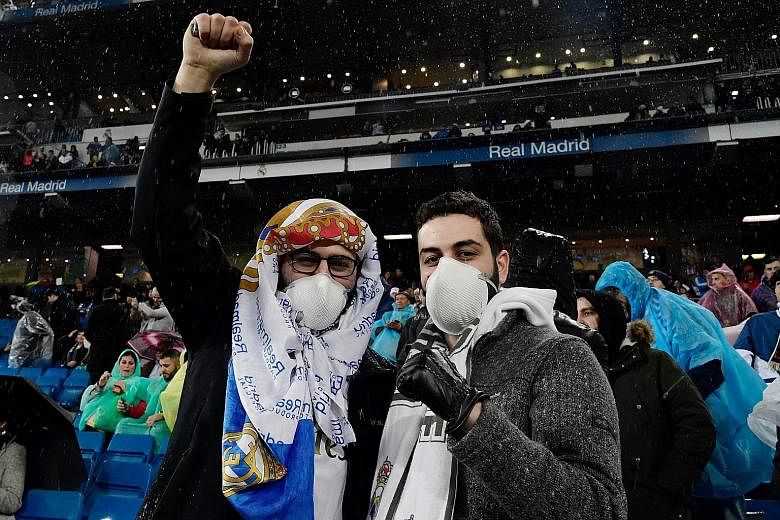 Two Real Madrid fans wearing masks in light of the coronavirus outbreak during the La Liga match against Barcelona at the Santiago Bernabeu on March 1. PHOTO: AGENCE FRANCE-PRESSE