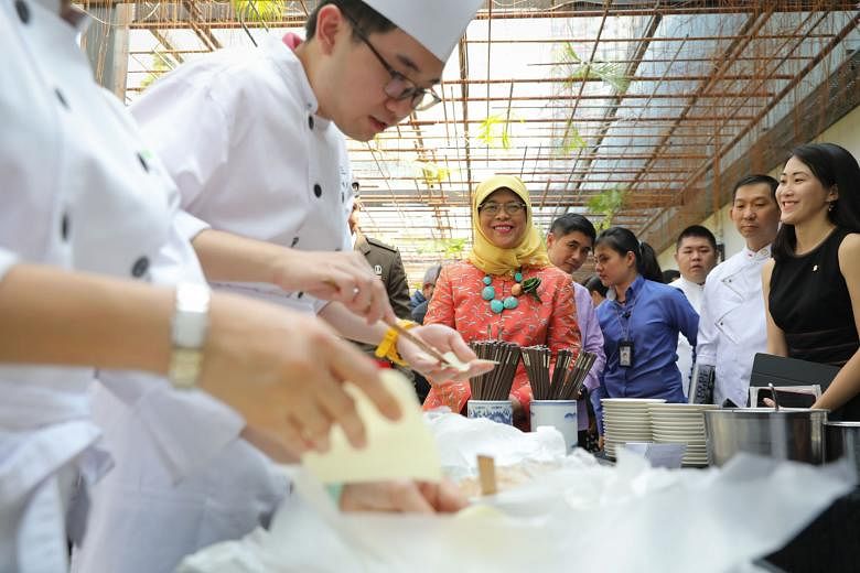 President Halimah Yacob learning about Mr Lau Chun Seng's (left) story. The 23-year-old has autism spectrum disorder and runs a noodle stall at Noodles for Good, a joint initiative by Si Chuan Dou Hua Restaurant, Autism Resource Centre and Central Si
