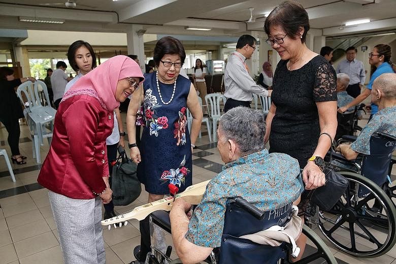 President Halimah Yacob, accompanied by Ling Kwang Home for Senior Citizens executive committee member Angelina Chua (centre) and director of nursing Lee Geok Yian (right), interacting with a senior citizen who participated in a music performance at 