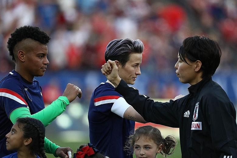 American players including Megan Rapinoe (top, centre), wearing their jerseys inside out in protest, bumping elbows with Japan players before their match in Texas. The US won 3-1 with Rapinoe scoring the first. PHOTOS: AGENCE FRANCE-PRESSE